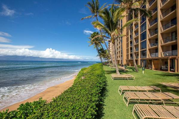 Mahana at Kaanapali Beach Maui resort, view of the beach and the oceanfront green lawn with chaise lounges. 
