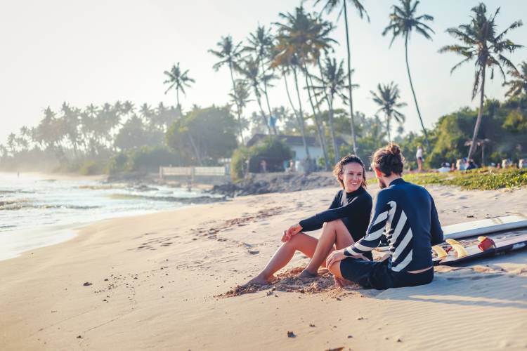 Sporty couple having fun surfing together at sunset on West Maui beach.