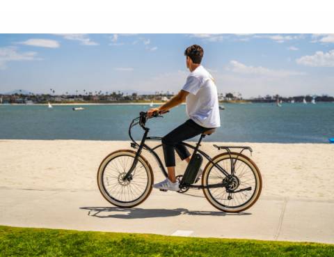 E-Bike Rental Man is riding an electric bike by the beach