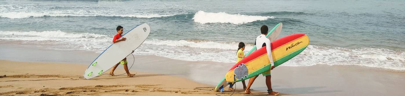Kids with surfboards are walking on Kaanapali beach