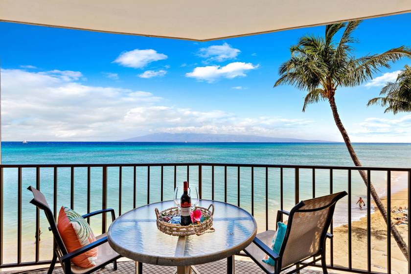 View from private lanai in a Valley Isle Resort vacation condo rental. The table is set with wine and palm trees sway in the foreground