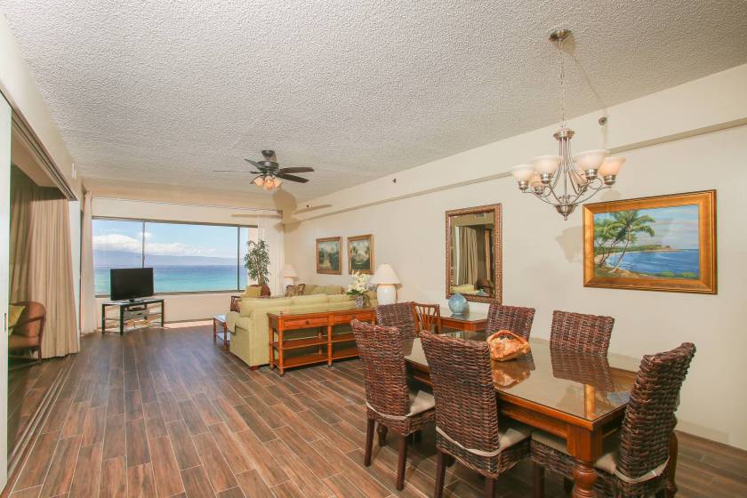 Spacious living room and dining area in a Sands of Kahana condo rental. The window is wide and features a view of the ocean.