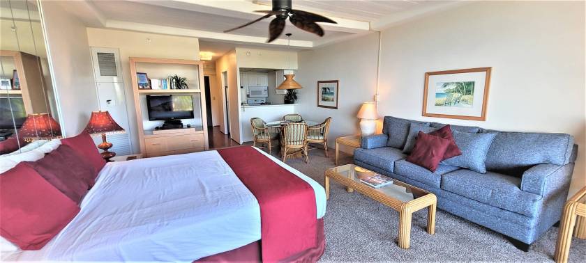 Spacious studio condo rental at the Whaler in Kaanapali, Maui, HI. It features a large bed, comfortable couch, kitchen, and dining area.